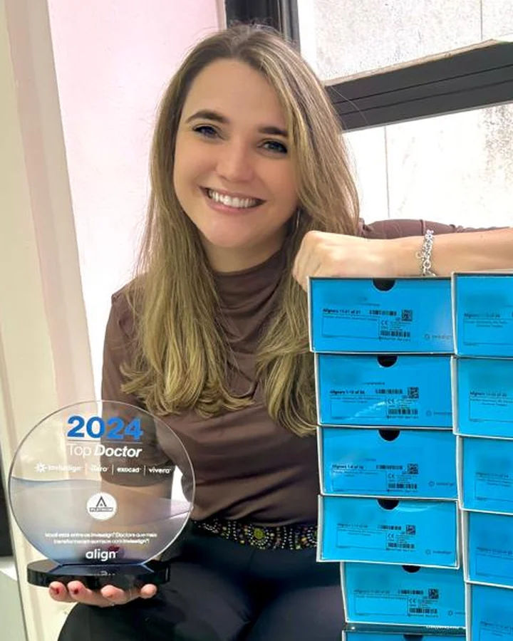 Dra. Isabela Lobo segurando o troféu Top Doctor 2024 da Align, ao lado de caixas de alinhadores Invisalign