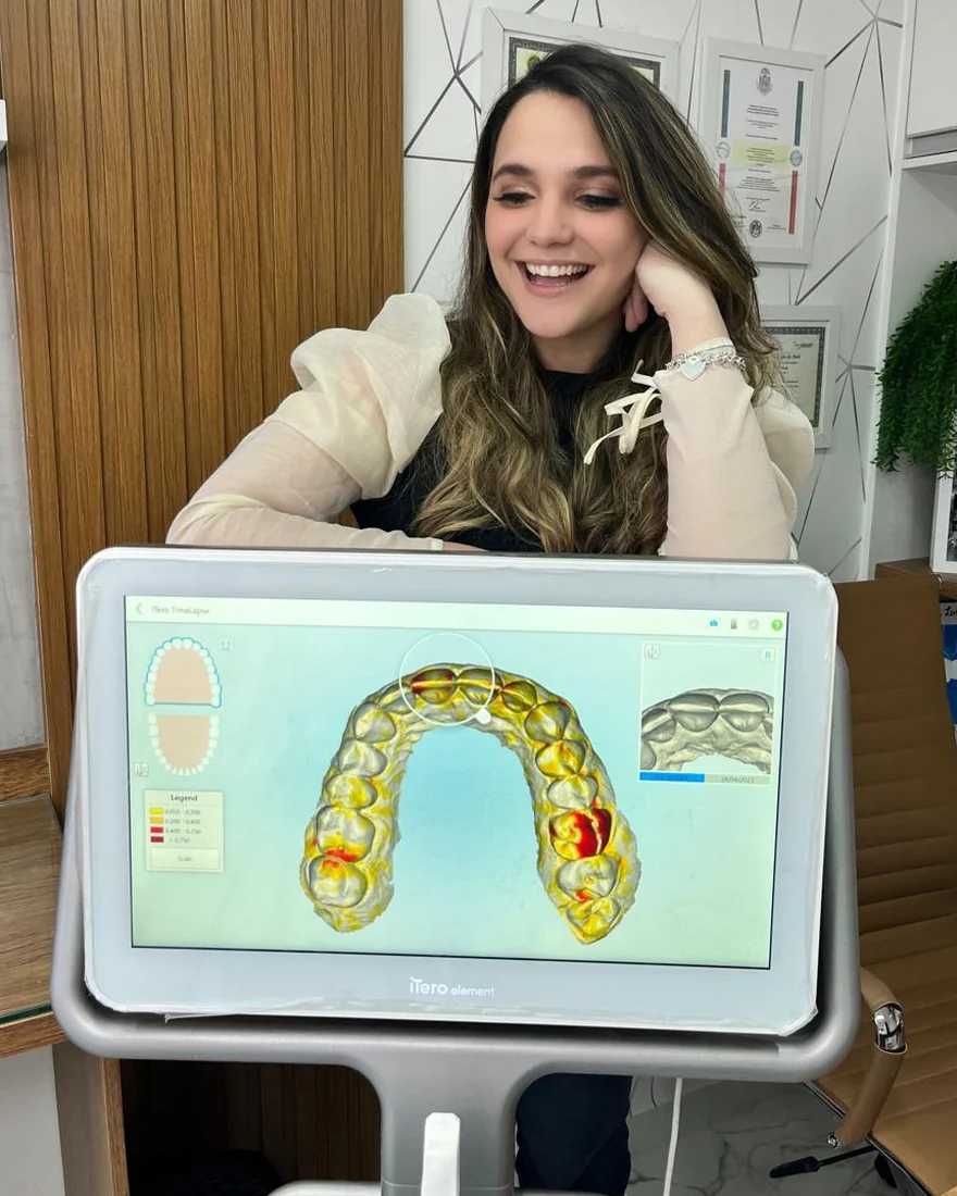 Dra. Isabela Lobo ao lado do scanner iTero, com o modelo 3D de uma arcada na tela